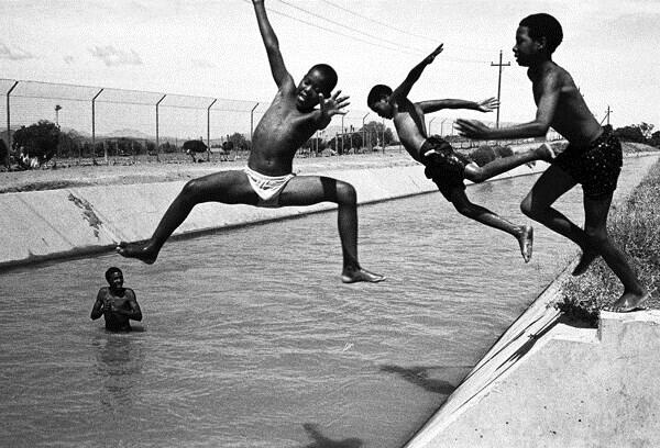 First day of the school holidays and 33 degrees Celsius; children from Bridgton township cool off in an irrigation canal near the abbatoir. South Africa, Dec. 8, 2003