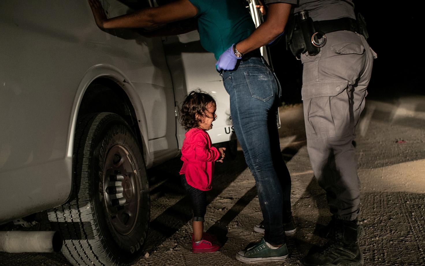 Фото было сделано в июне 2018 года на границе США и Мексики. Маленькая девочка, на глазах у которой пограничник обыскивает мать, горько плачет.