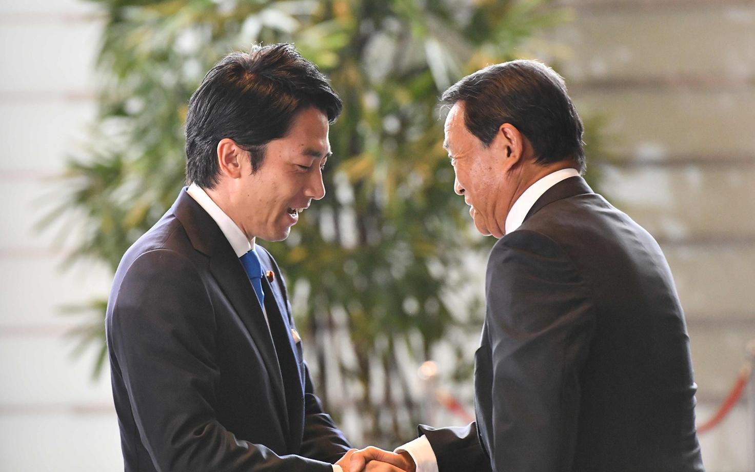 Värske keskkonnaminister Shinjiro Koizumi surub kätt asepeaministril ja rahandusministril Taro Asol