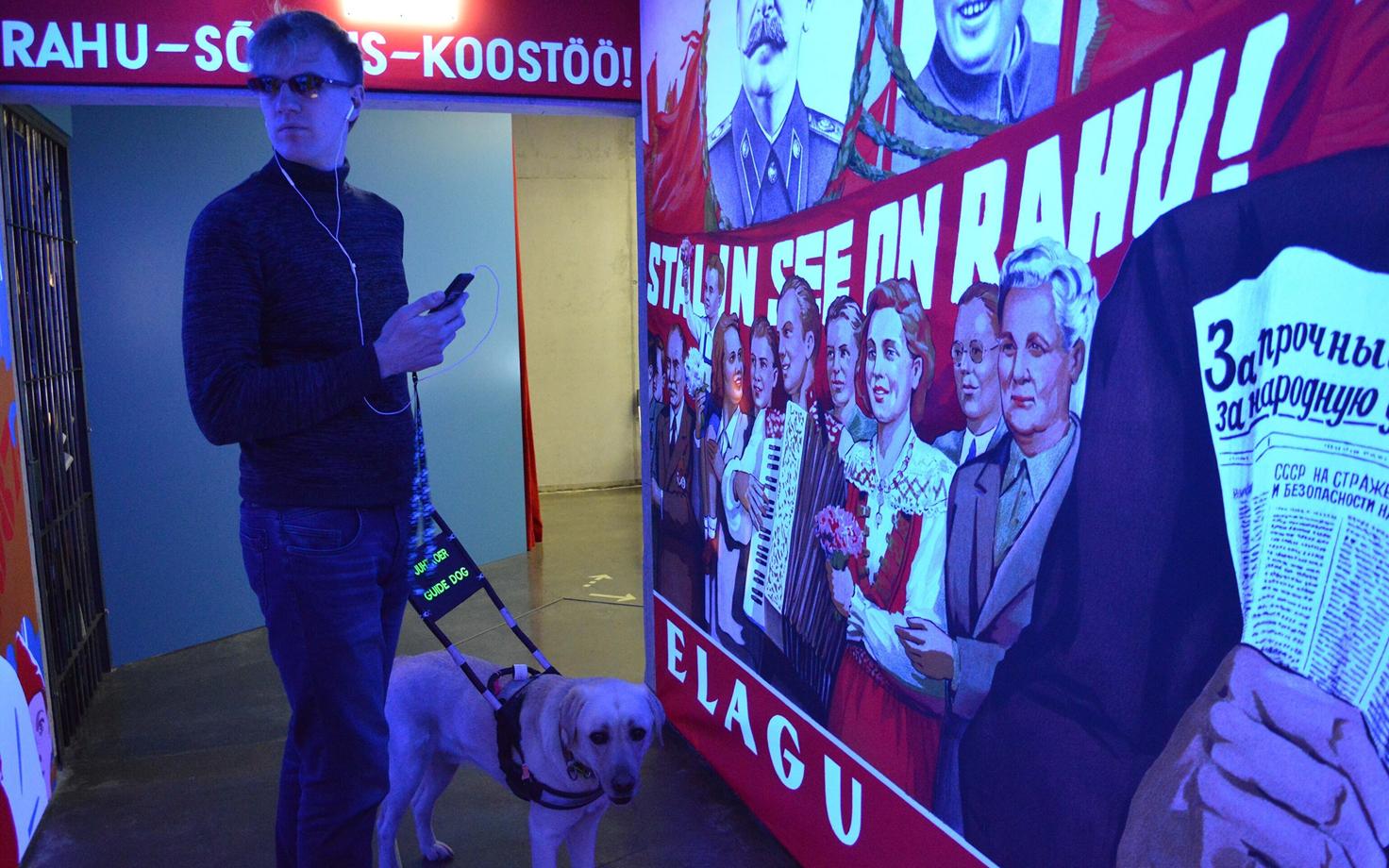 Jakob Jõgisuu, Põhja-Eesti Pimedate Ühingu liige külastamas Vabamu püsinäitust juhtkoeraga.