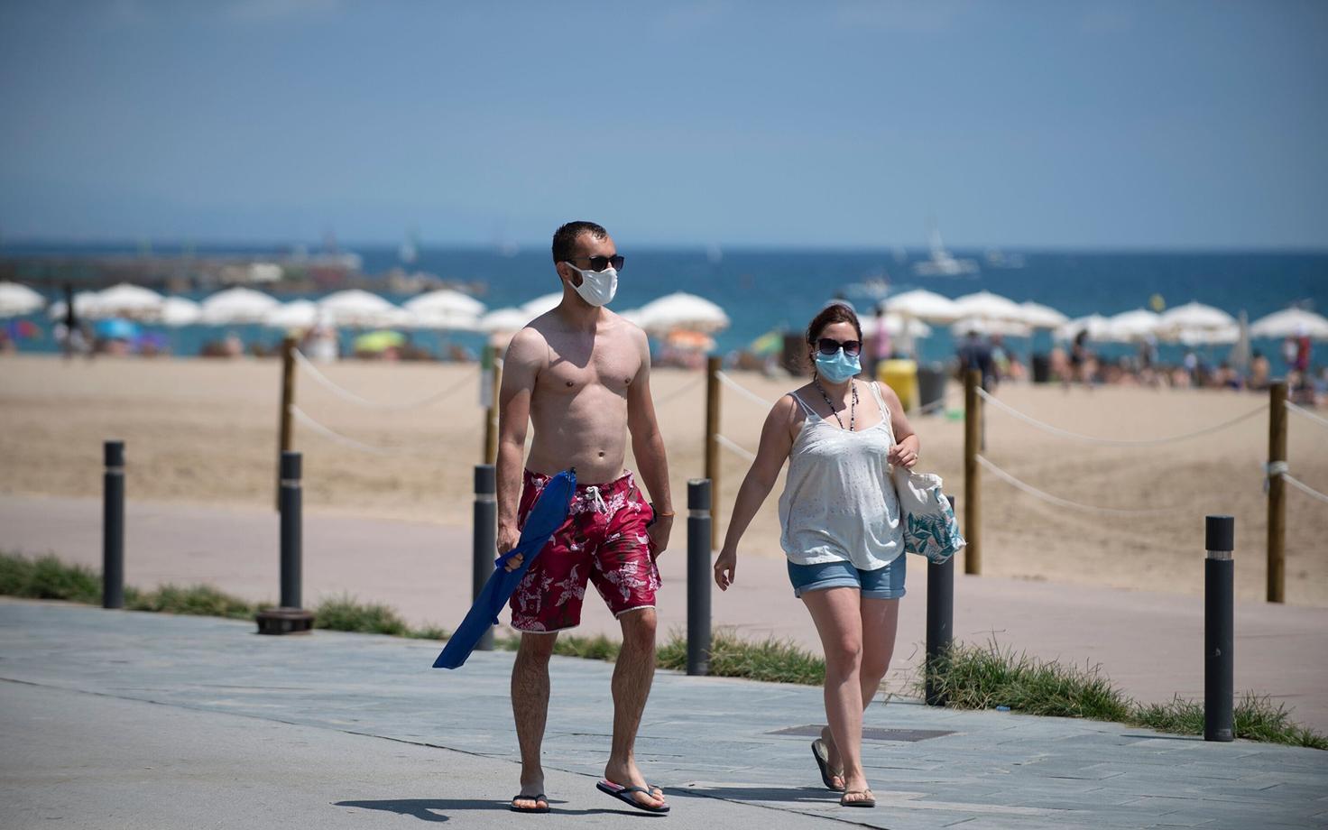 Maskidega inimesed Barcelona rannas.