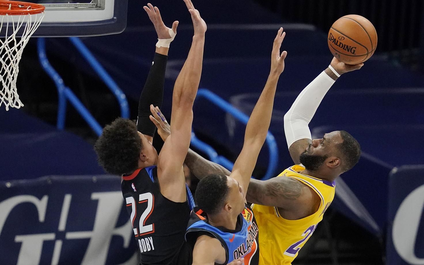 LeBron James viskel, Isaiah Roby (22) ja Darius Bazley püüavad teda takistada