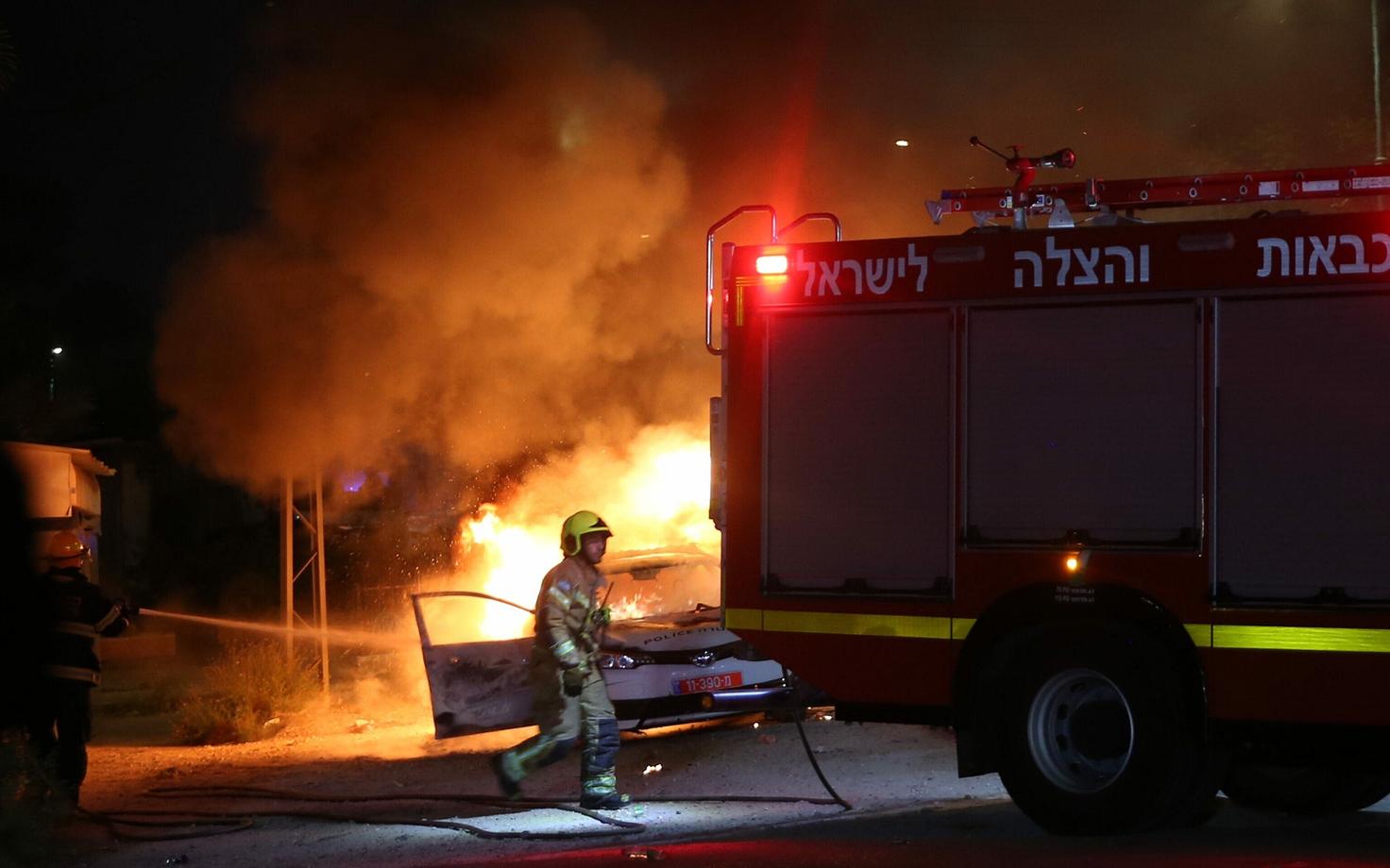 Iisraeli tuletõrjujad põleva politseiauto juures Lodi linnas.