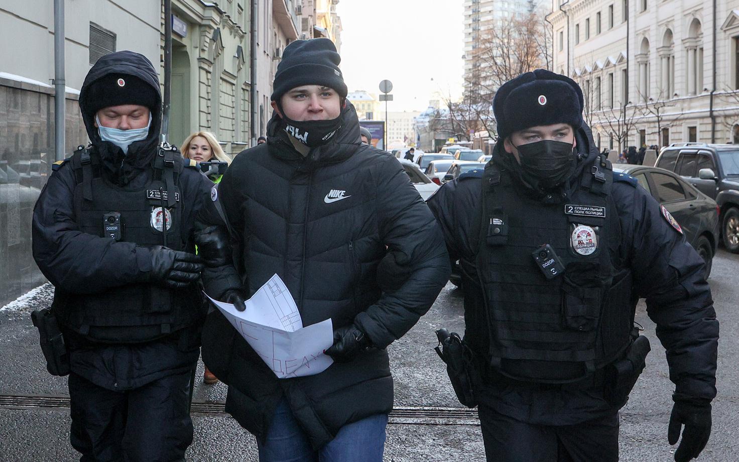 Полицейские уводят человека, участвовавшего в пикете в поддержку общества