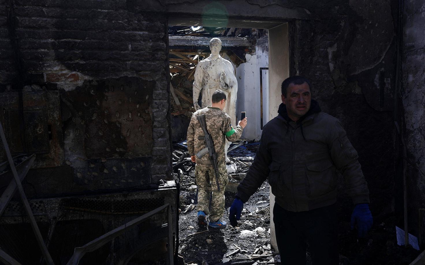 Ukraina sõdur filmimas pommirünnaku tagajärgi Harkivi lähistel muuseumis Ukraina filosoofi Grigori Skovoroda kuju kõrval.