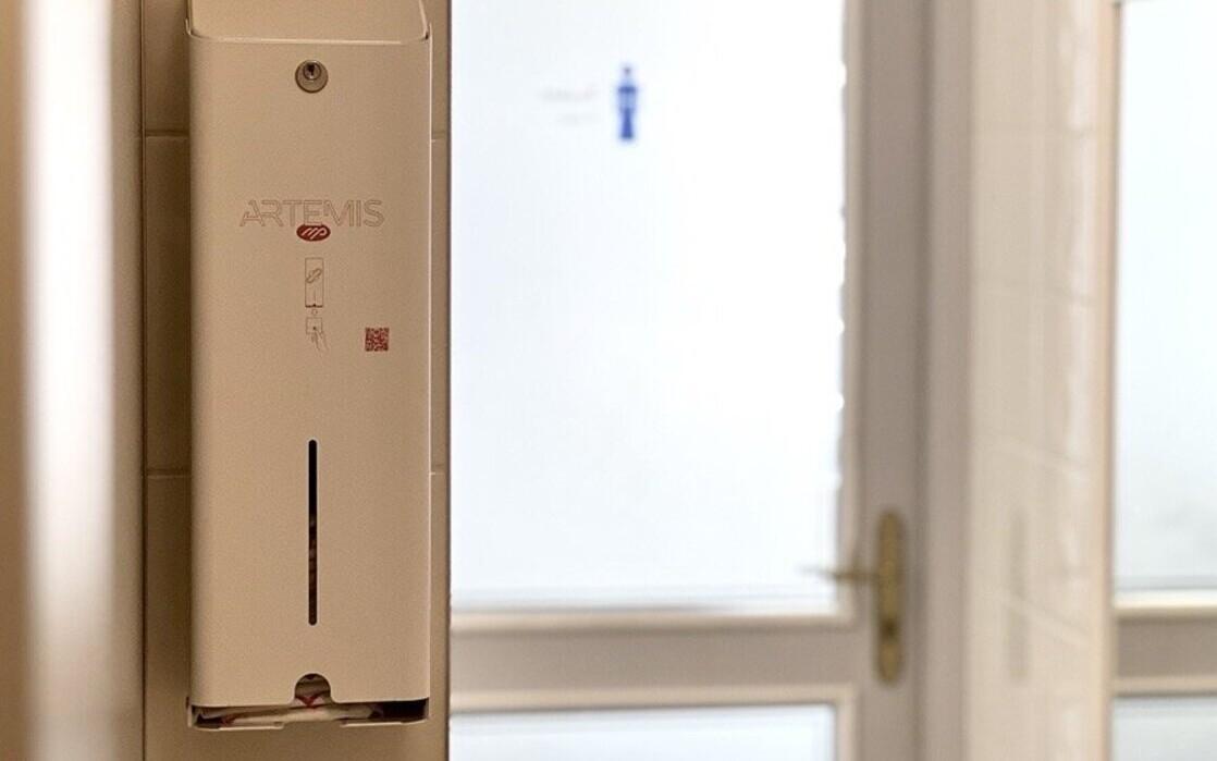 A menstrual pad dispenser in a public bathroom.