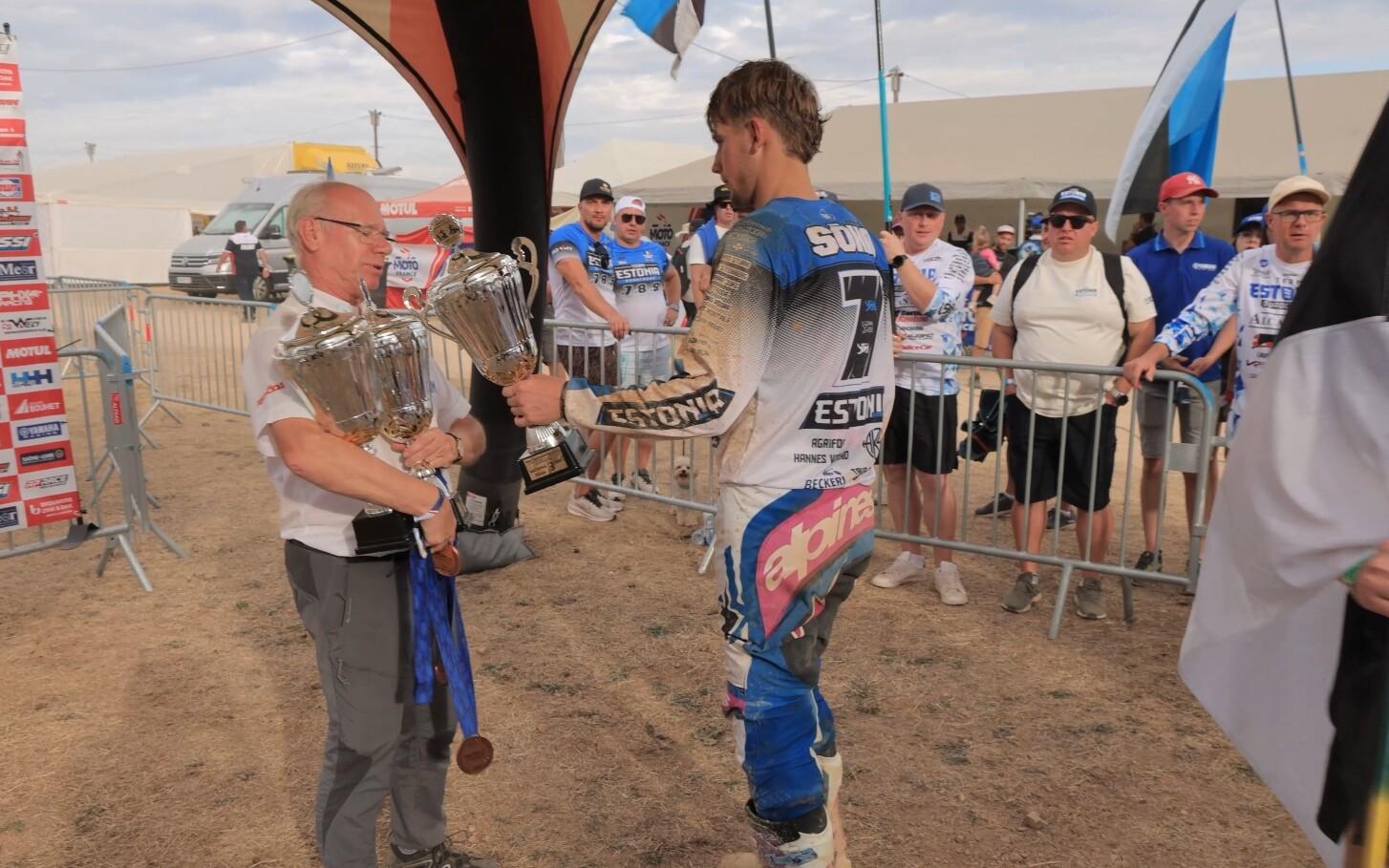 Rasmus Sõna handing back his third-place trophy to an event organizer.