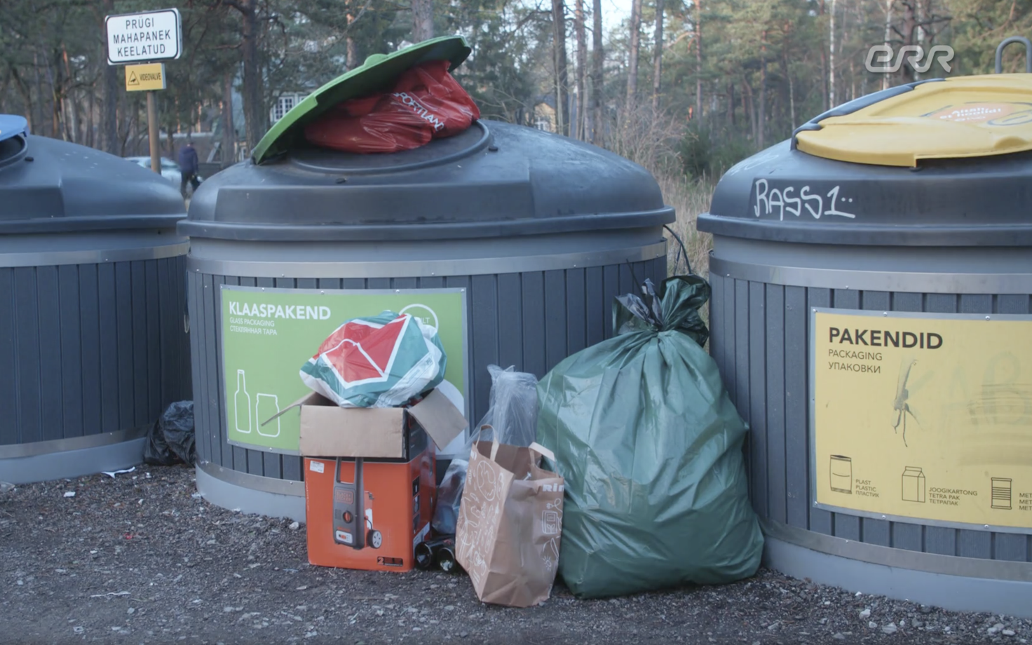 Waste piled up next to an overflowing public recycling dumpster.